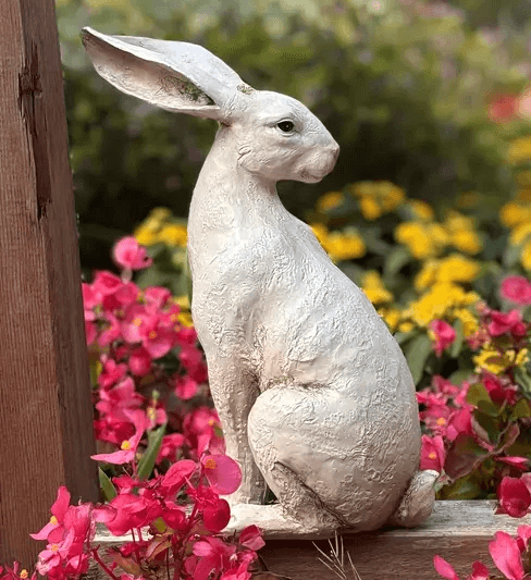 Seated lifelike rabbit sculpture with upright ears, surrounded by flowers, created using silicone mold


