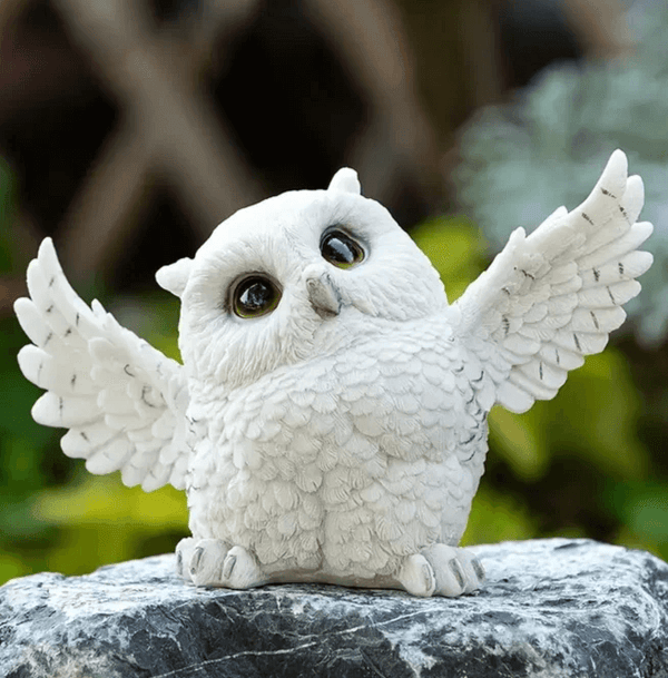 White owl figure with spread wings and feather detail, created using silicone mold in forest setting


