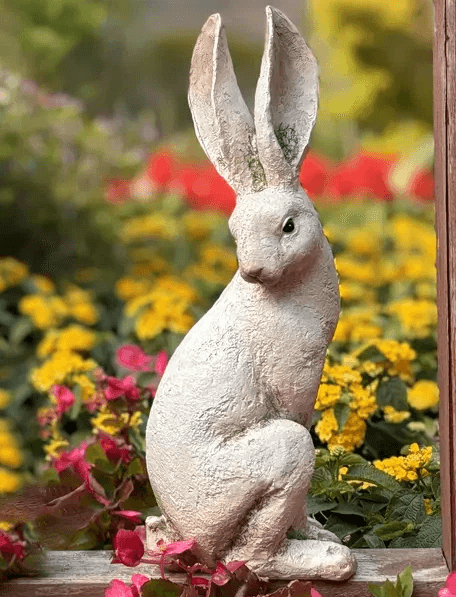 Standing white rabbit figure with tall ears in alert pose, created using silicone mold and displayed in garden setting


