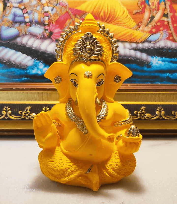 Yellow resin casting of Lord Ganesha in seated pose with crown and raised hand, created using silicone mold for candle and soap making