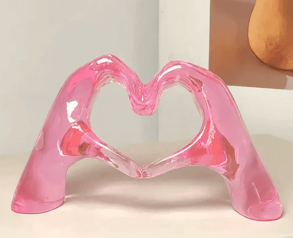 Pink resin casting of two hands forming a heart shape, created using silicone mold for romantic resin making projects