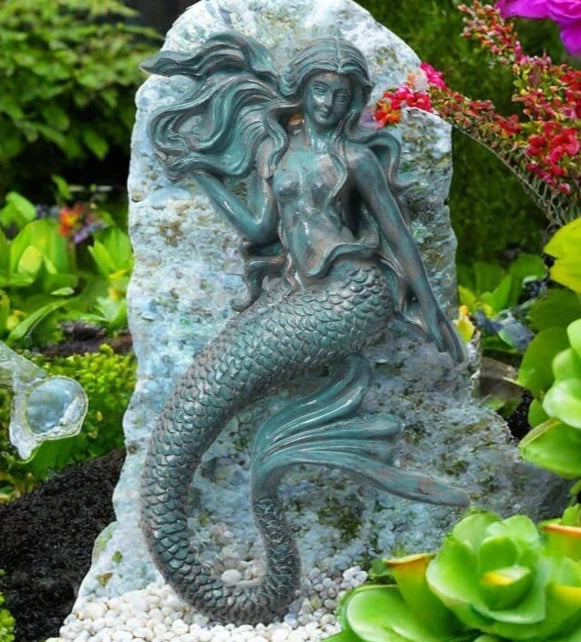 Mermaid wall figure with arched tail and long hair, resting among flowers, created using silicone mold


